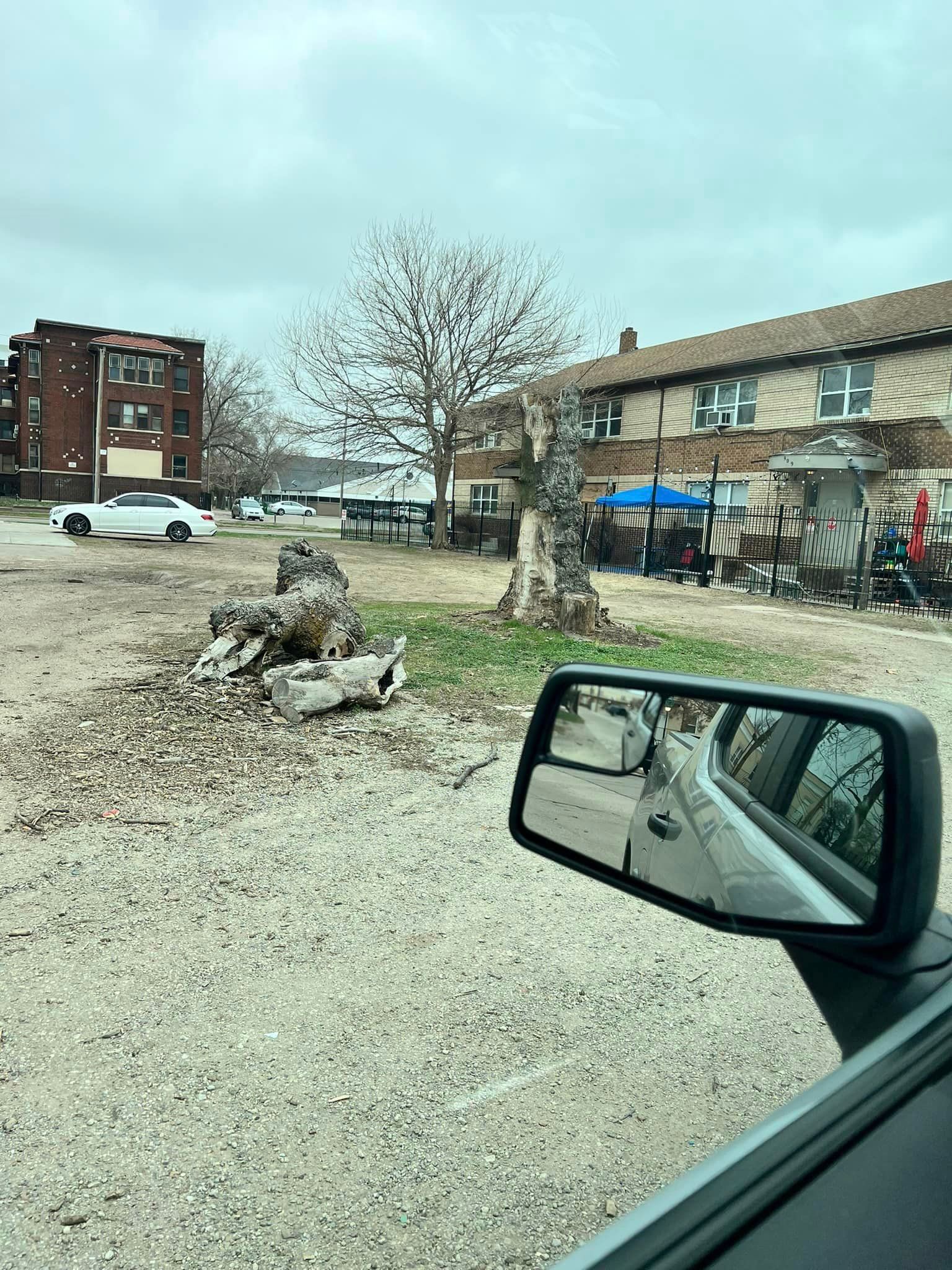 A car is parked in a gravel lot in front of a building.
