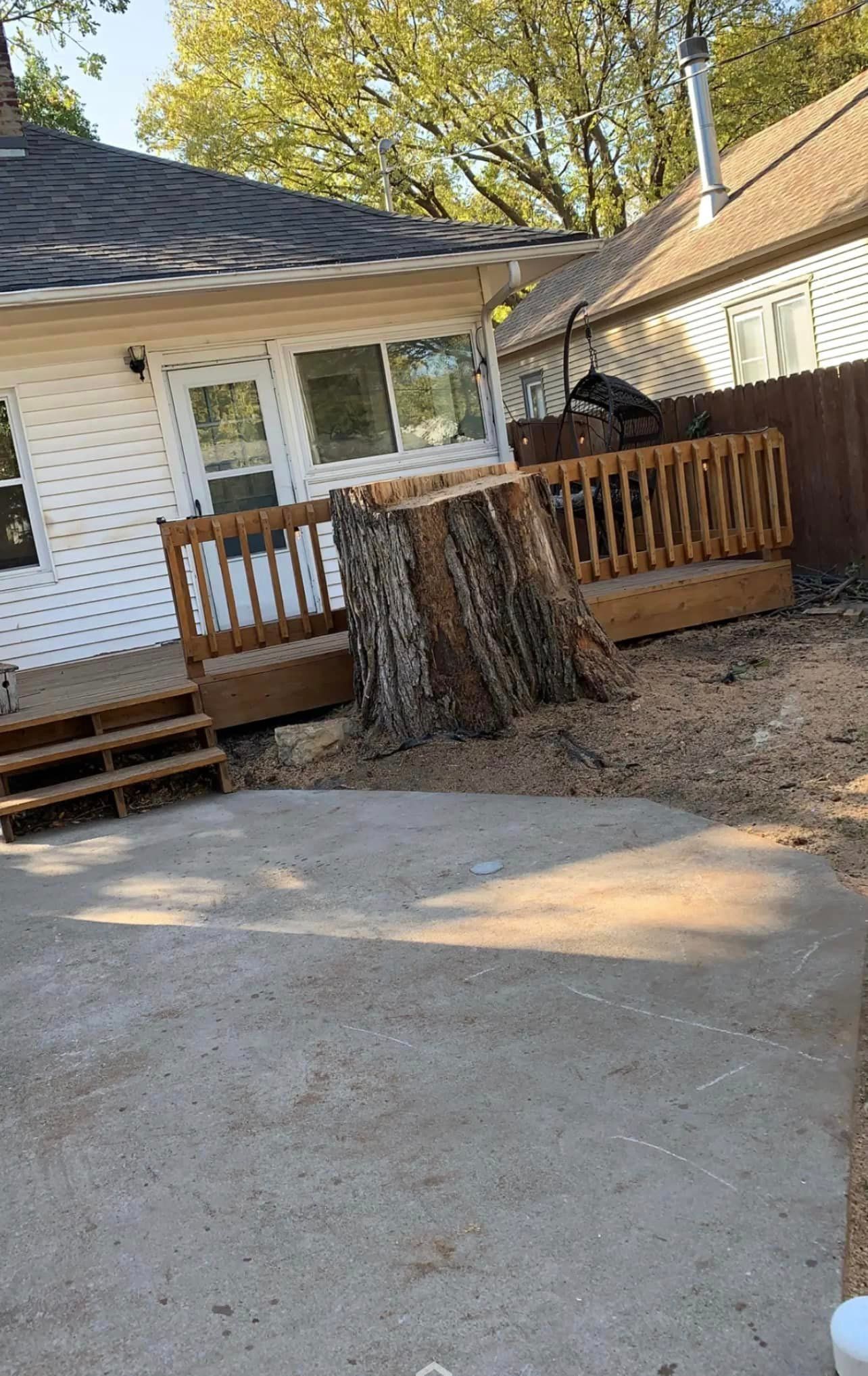 A large tree stump is sitting in front of a house.