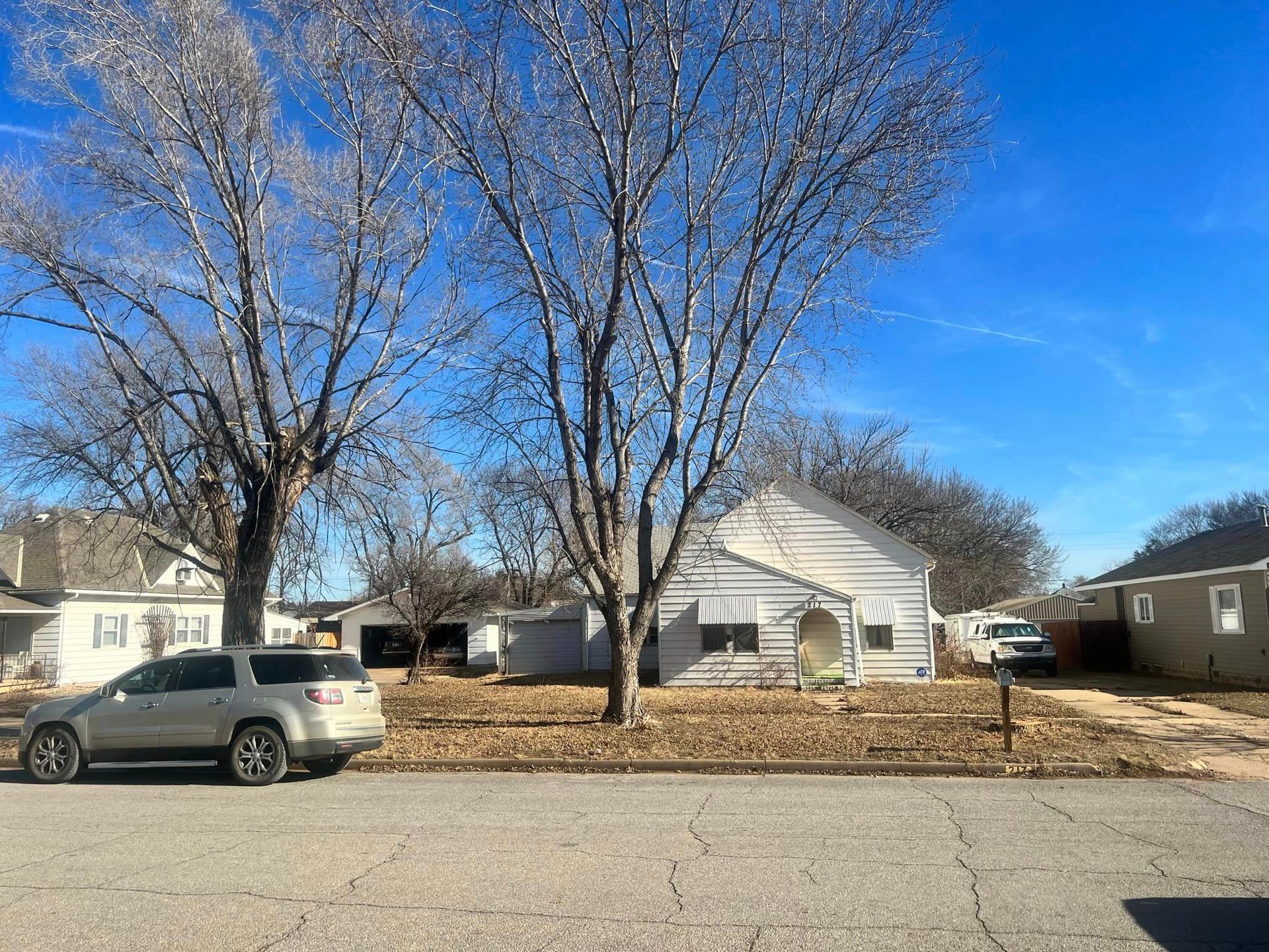 A car is parked on the side of the road in front of a house.