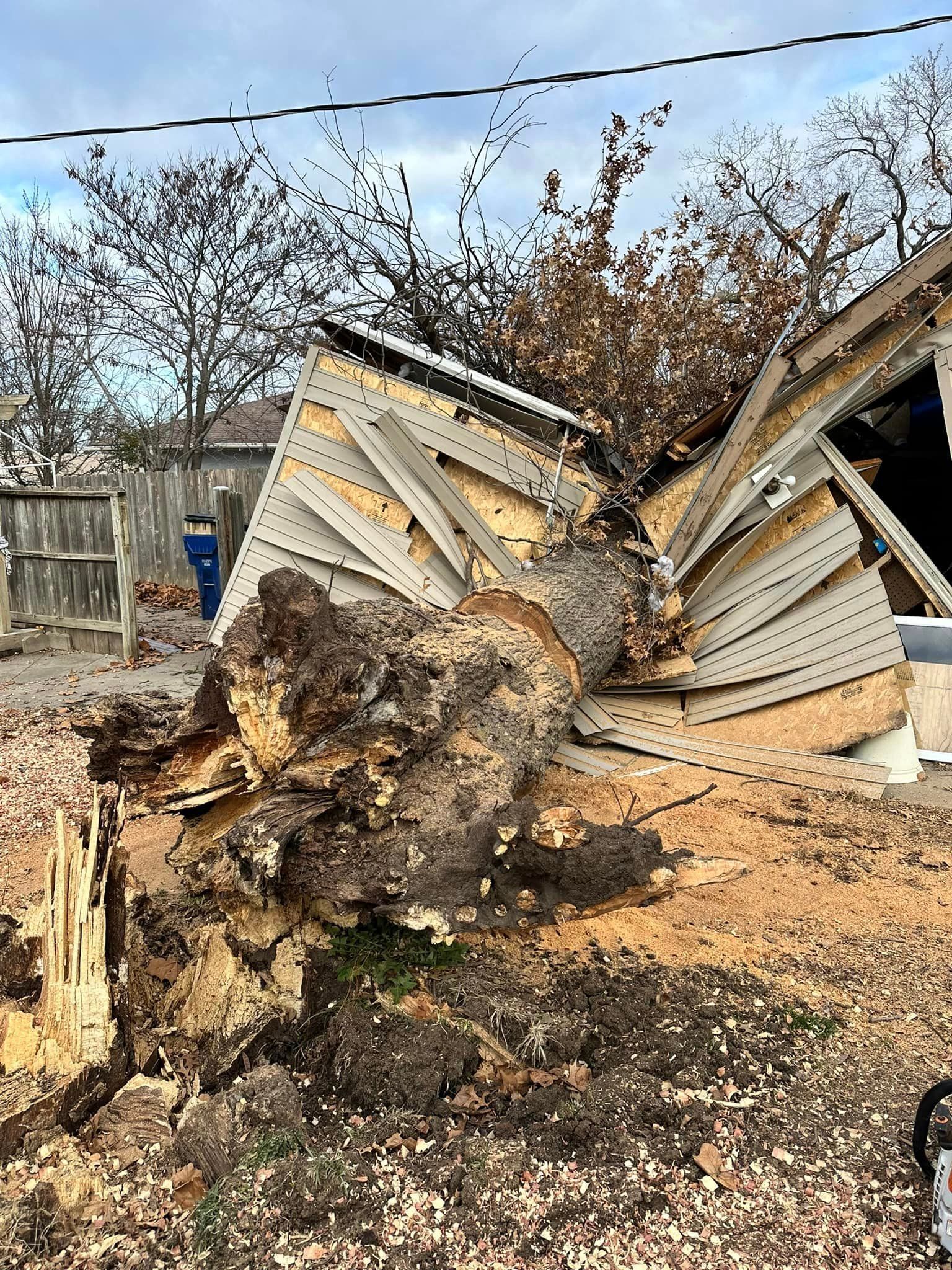 A large tree stump is laying on the ground next to a fallen building.