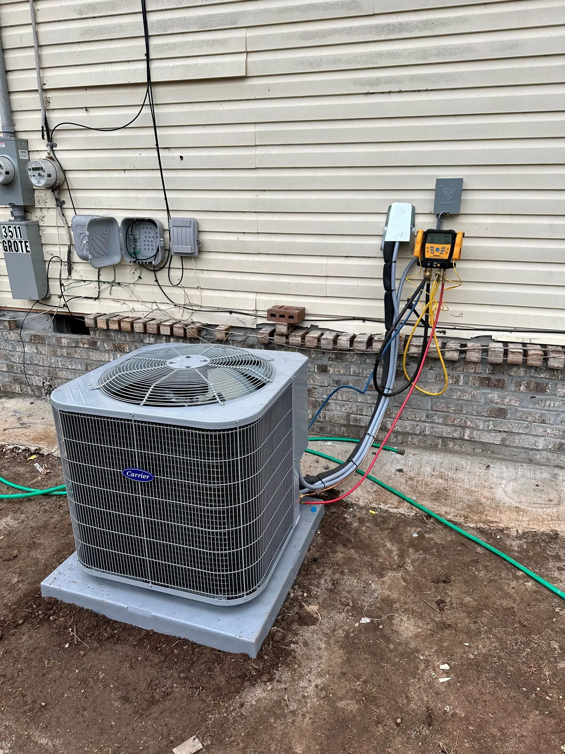 An air conditioning unit outside a building with electrical wiring connected to it.