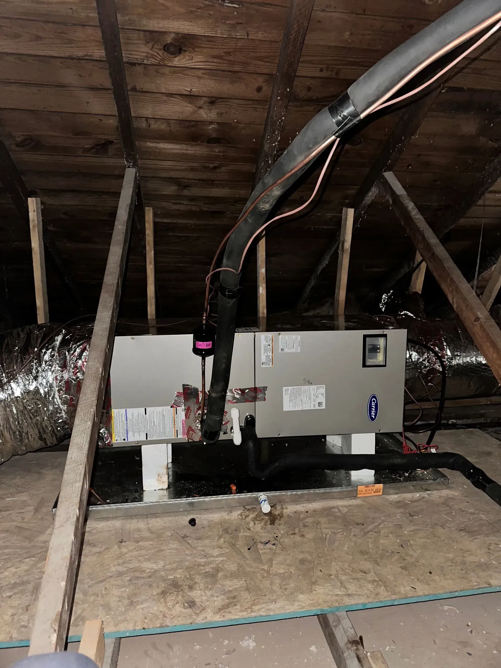 An HVAC unit installed in an attic with insulated ducts.