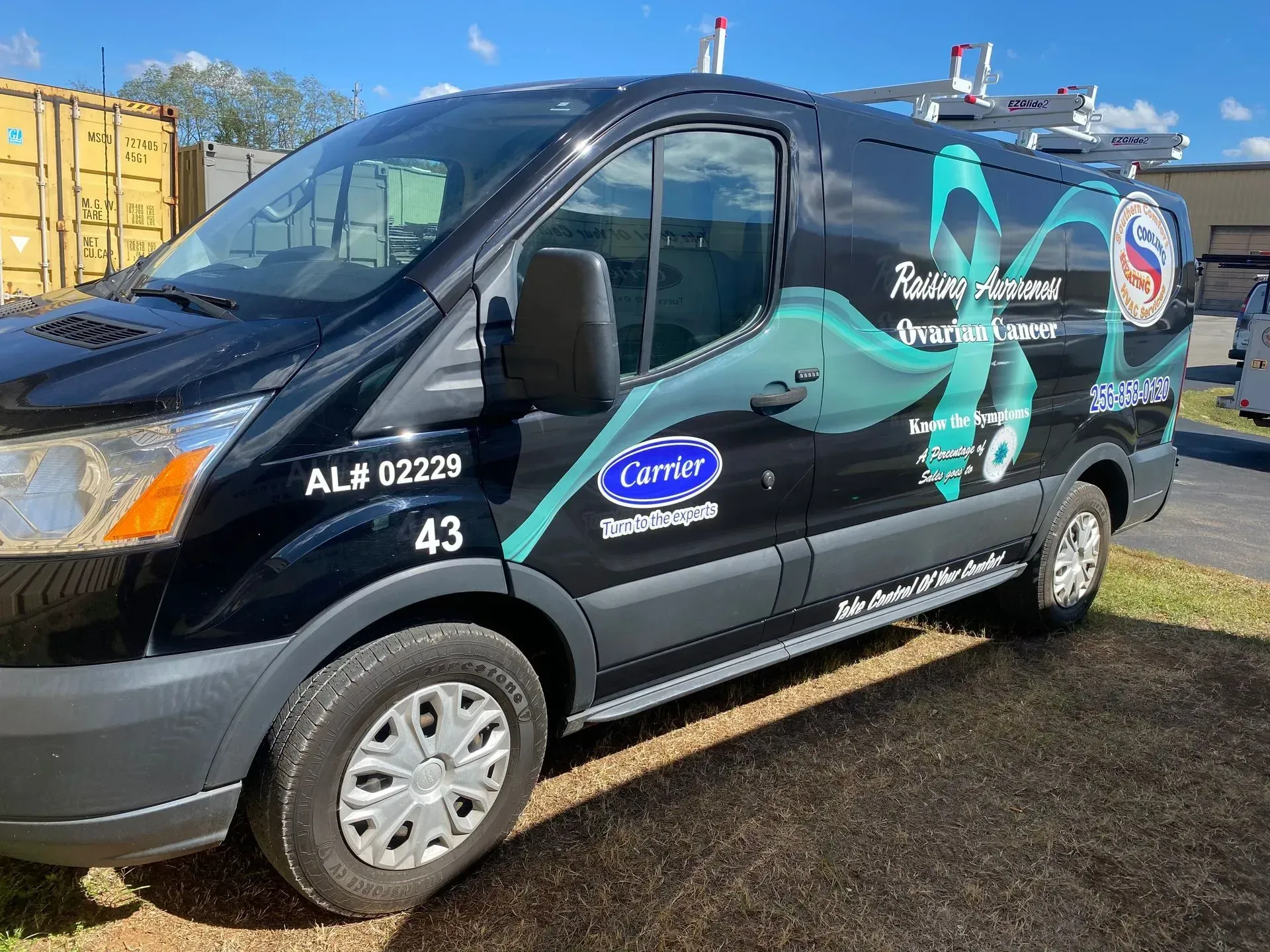 Black HVAC service van with Carrier logo, parked outdoors.