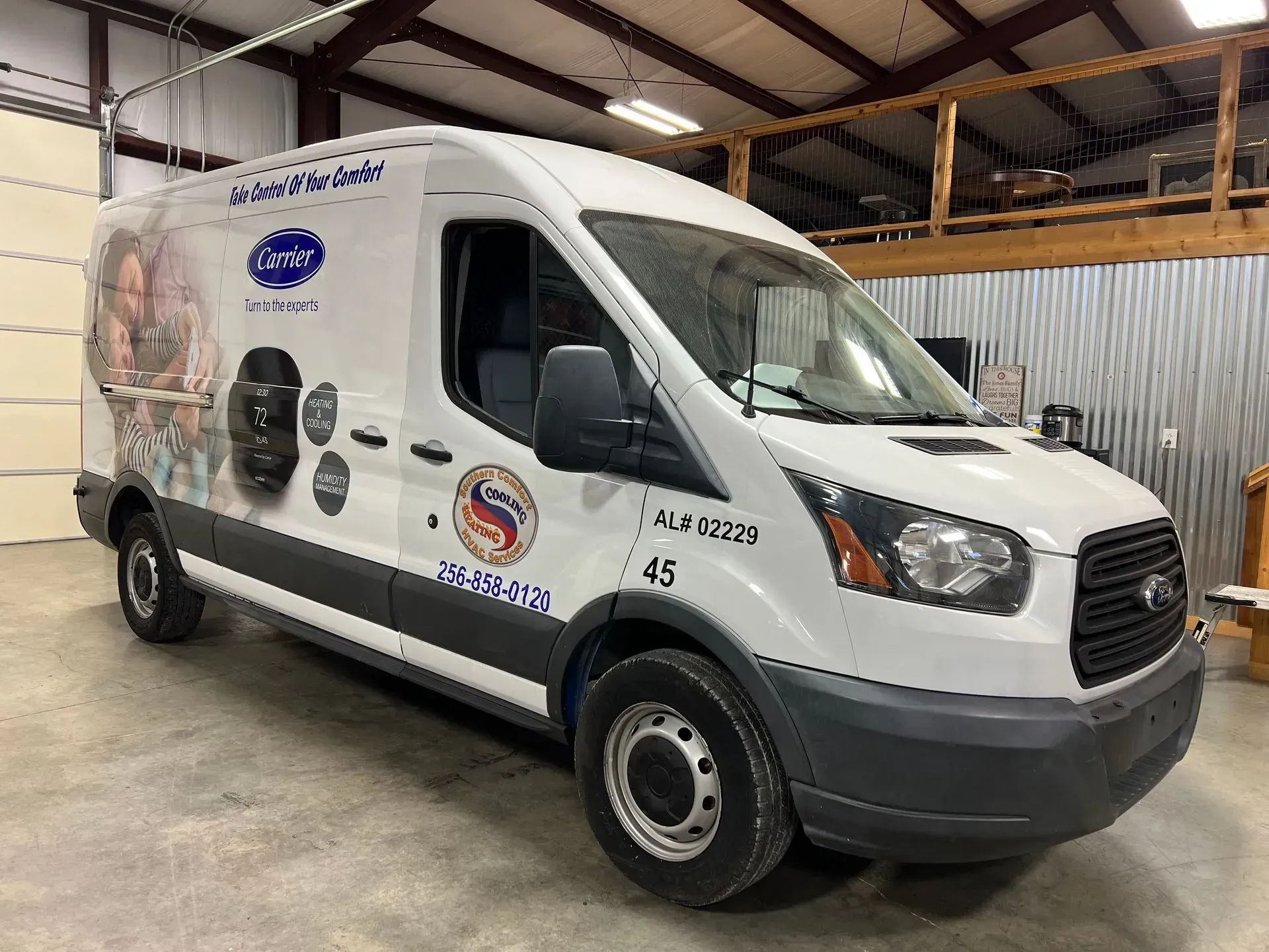 White Ford Transit van with company graphics parked indoors.