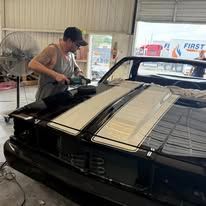 A man is working on a black car in a garage.