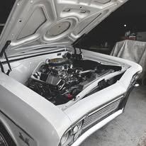 A black and white photo of a white car with the hood open.