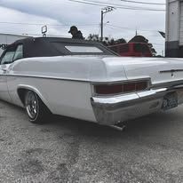 A white car is parked in a parking lot next to a truck.