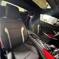 The interior of a black car with a red trim and a sunroof.