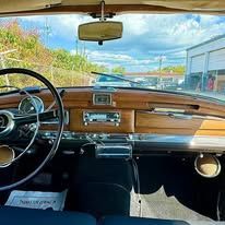 The interior of a car with a steering wheel and a rear view mirror.