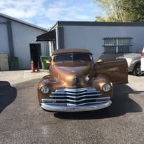 A brown car is parked in a parking lot in front of a building.