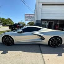 A silver sports car is parked in front of a garage.