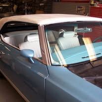 A blue car with a white roof is parked in a garage.