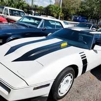 A white corvette with black stripes is parked in a parking lot.