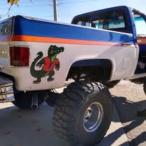 A blue and white truck with a crocodile sticker on the back of it.