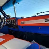 The interior of a blue and orange truck with a steering wheel and dashboard.