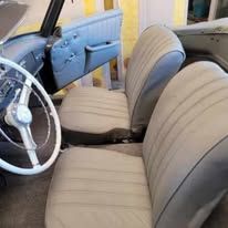 The interior of a car with a steering wheel and seats.