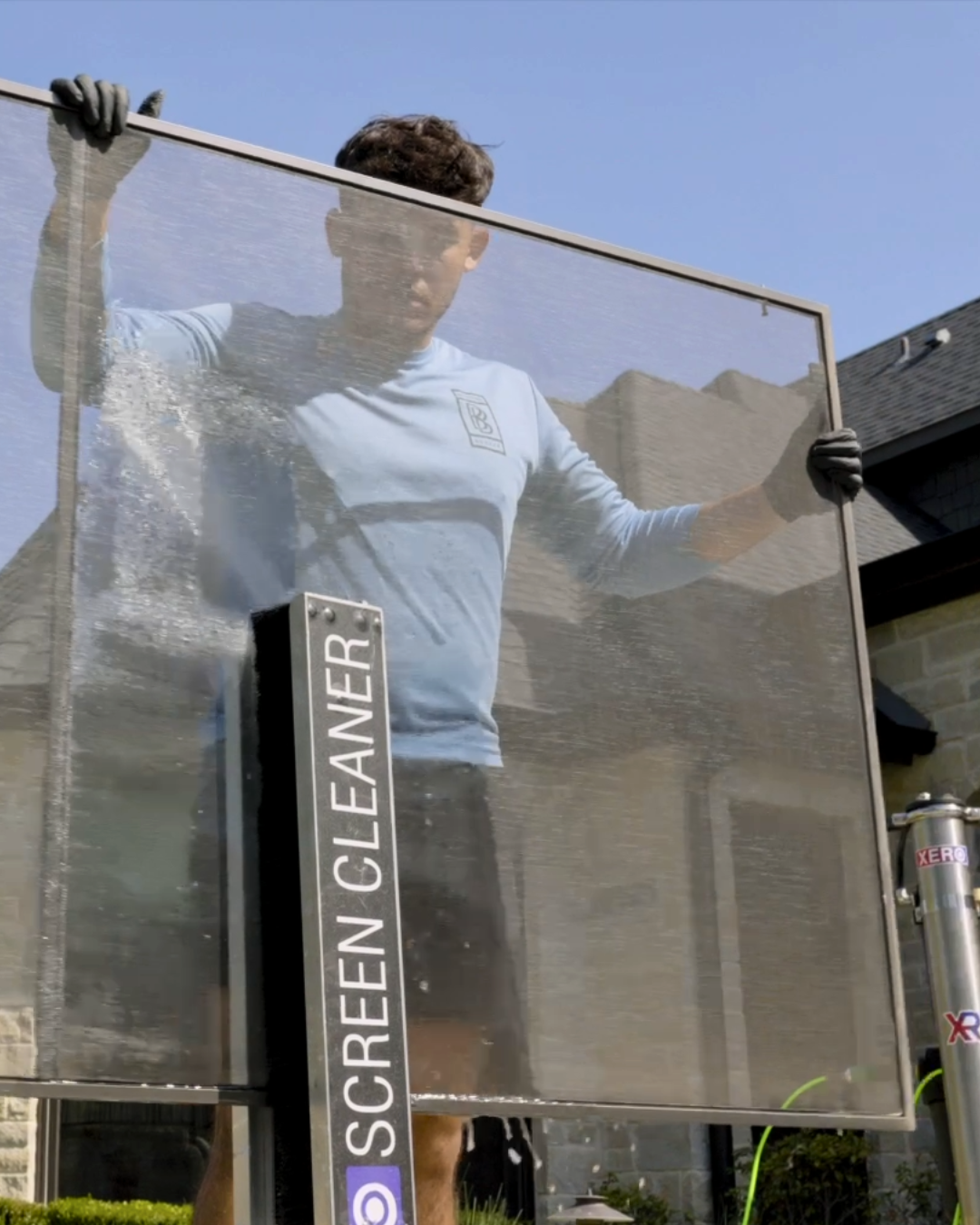 A man holding a screen cleaner in front of a house