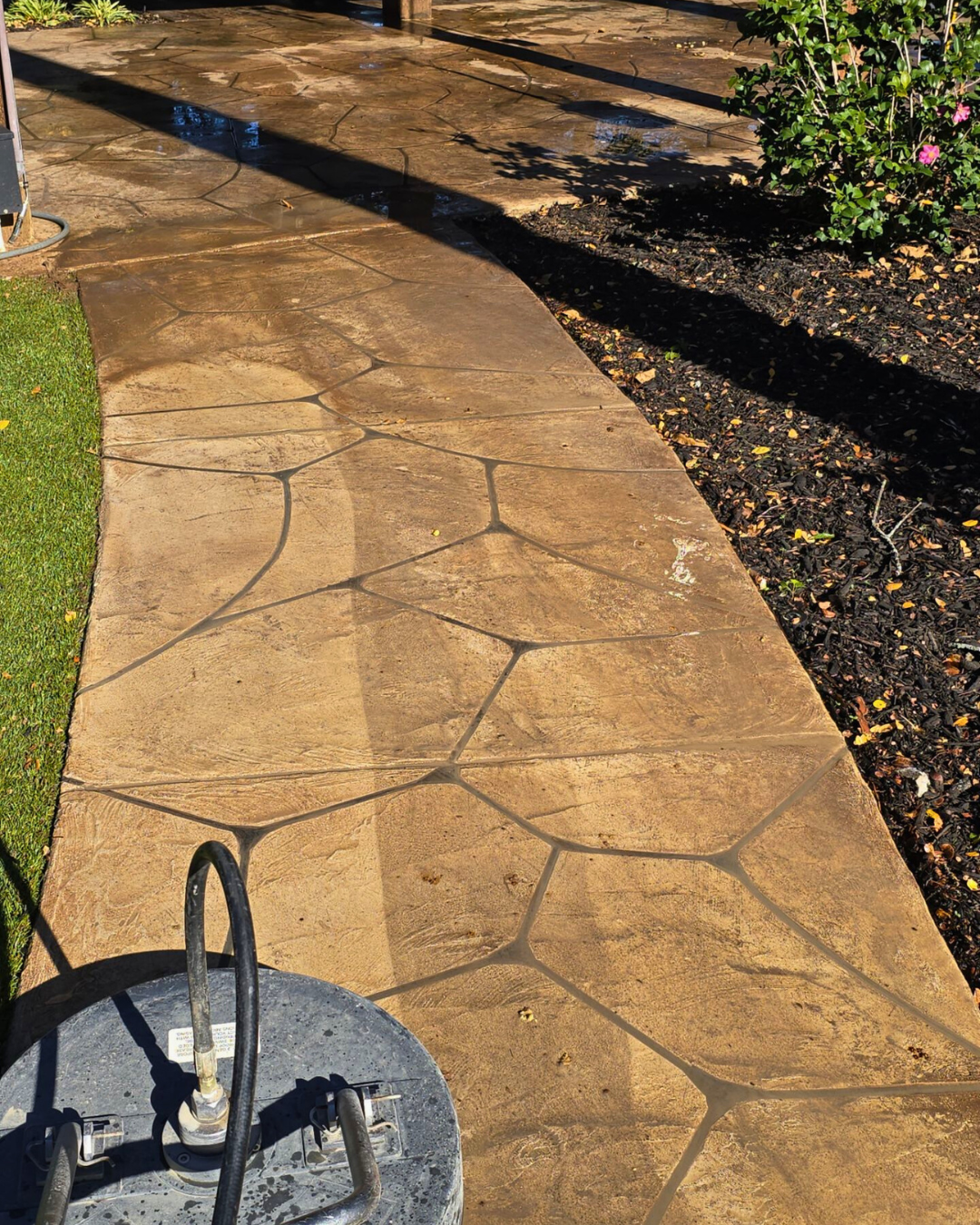 A concrete walkway with a water heater on the side of it.