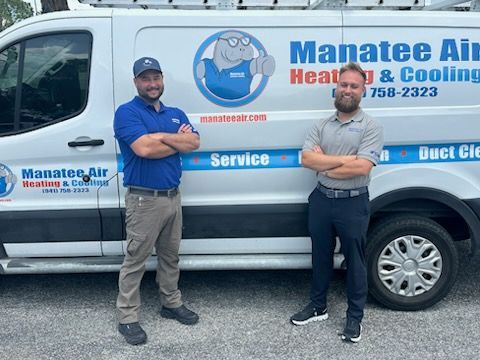 Two men standing in front of a Manatee Air Heating & Cooling service van.