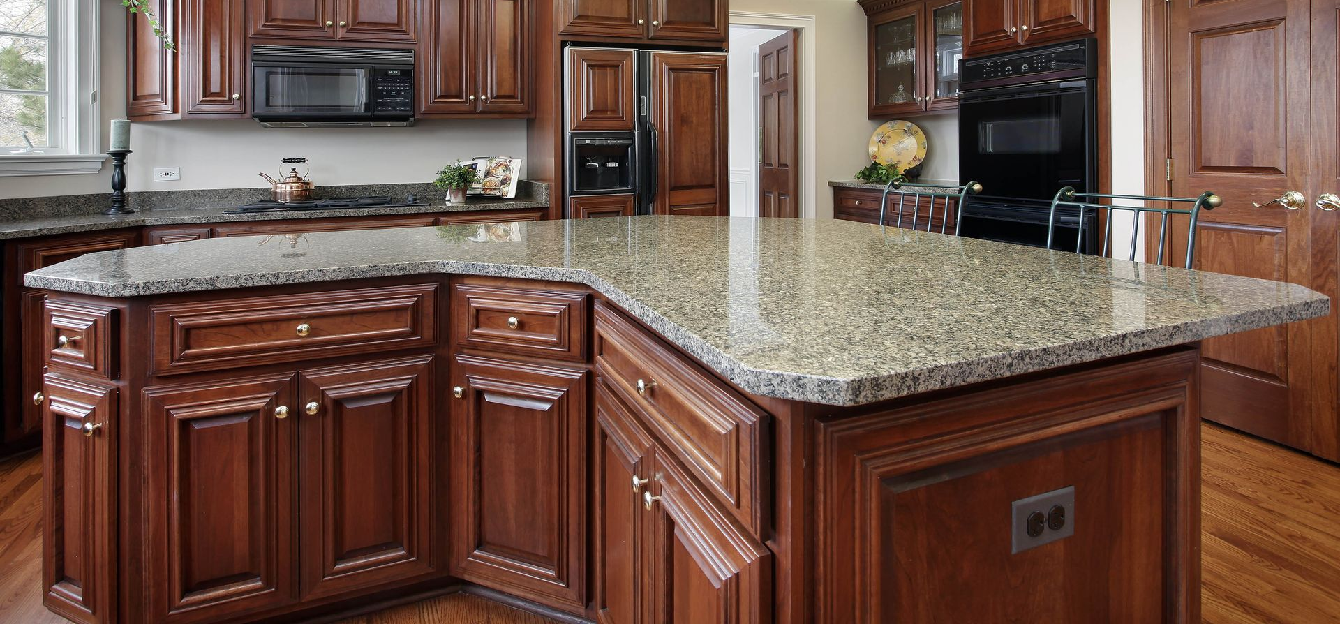 Modern kitchen with dark wood cabinets, granite island countertop, and stainless steel appliances