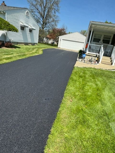 A driveway leading to a house with a lush green lawn