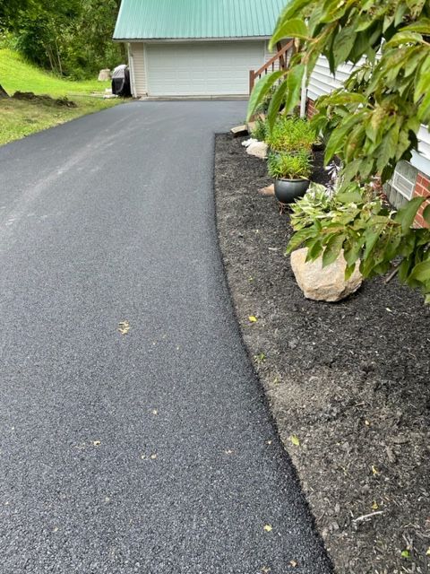 A driveway leading to a house with a green roof