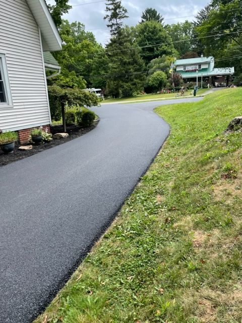 A driveway leading to a house with a white house in the background