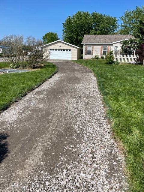 A gravel driveway leading to a house with a garage