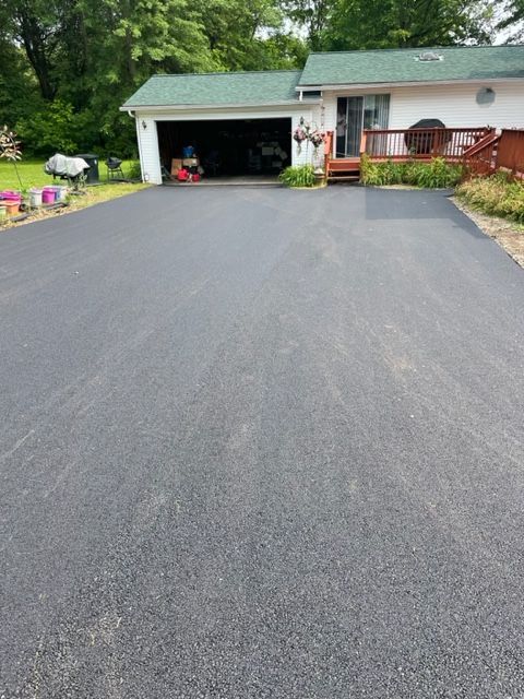 A driveway leading to a house with a garage and a deck