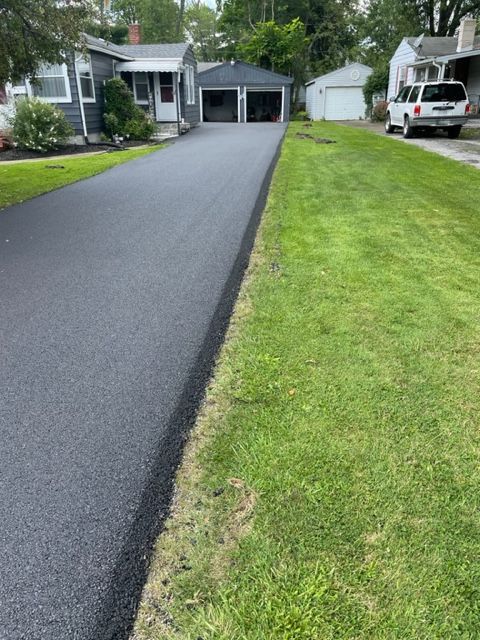 A driveway leading to a house with a white truck parked on the side of it