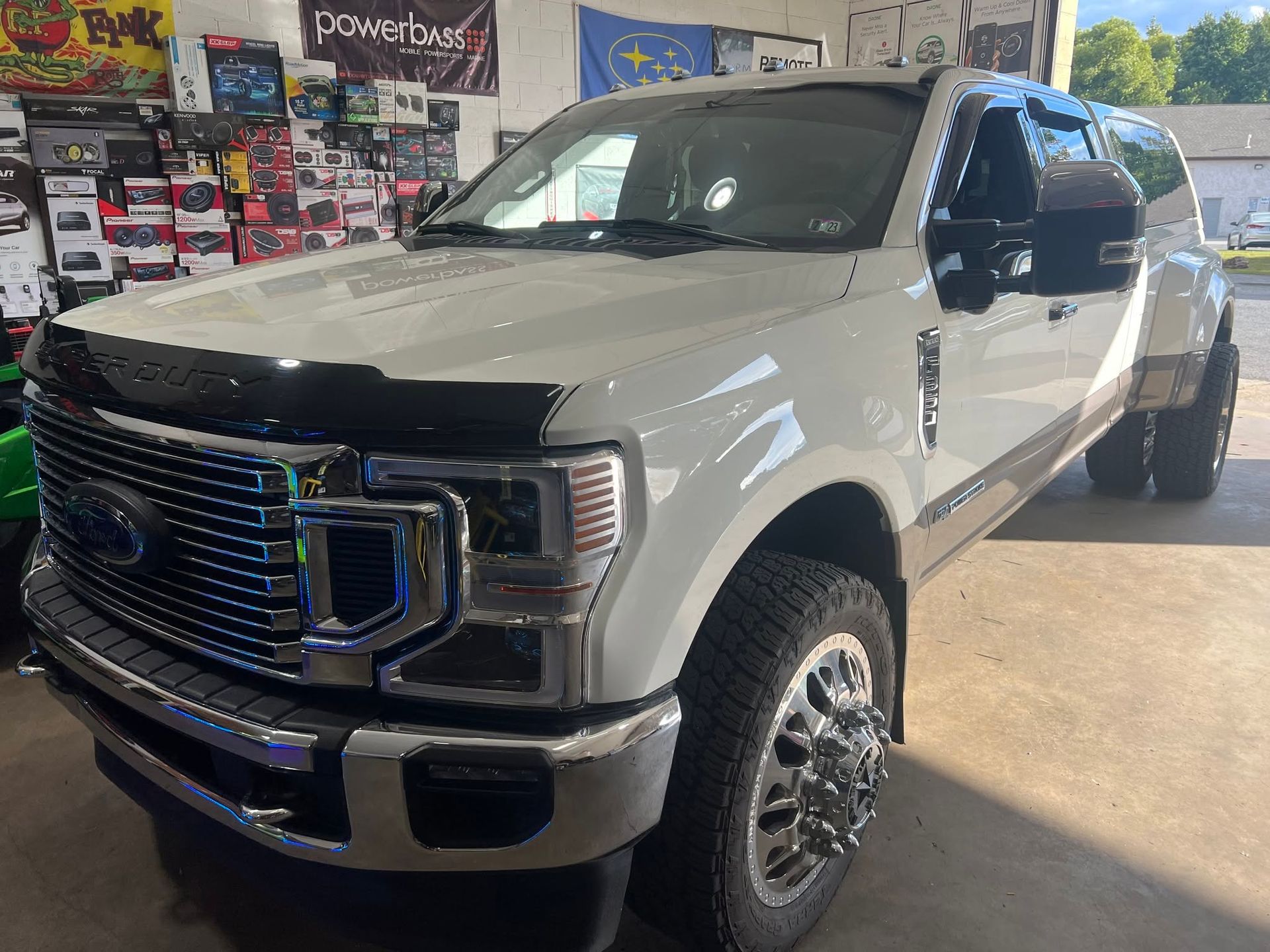 White Ford pickup truck parked indoors, viewed from the front-left in a garage or showroom.