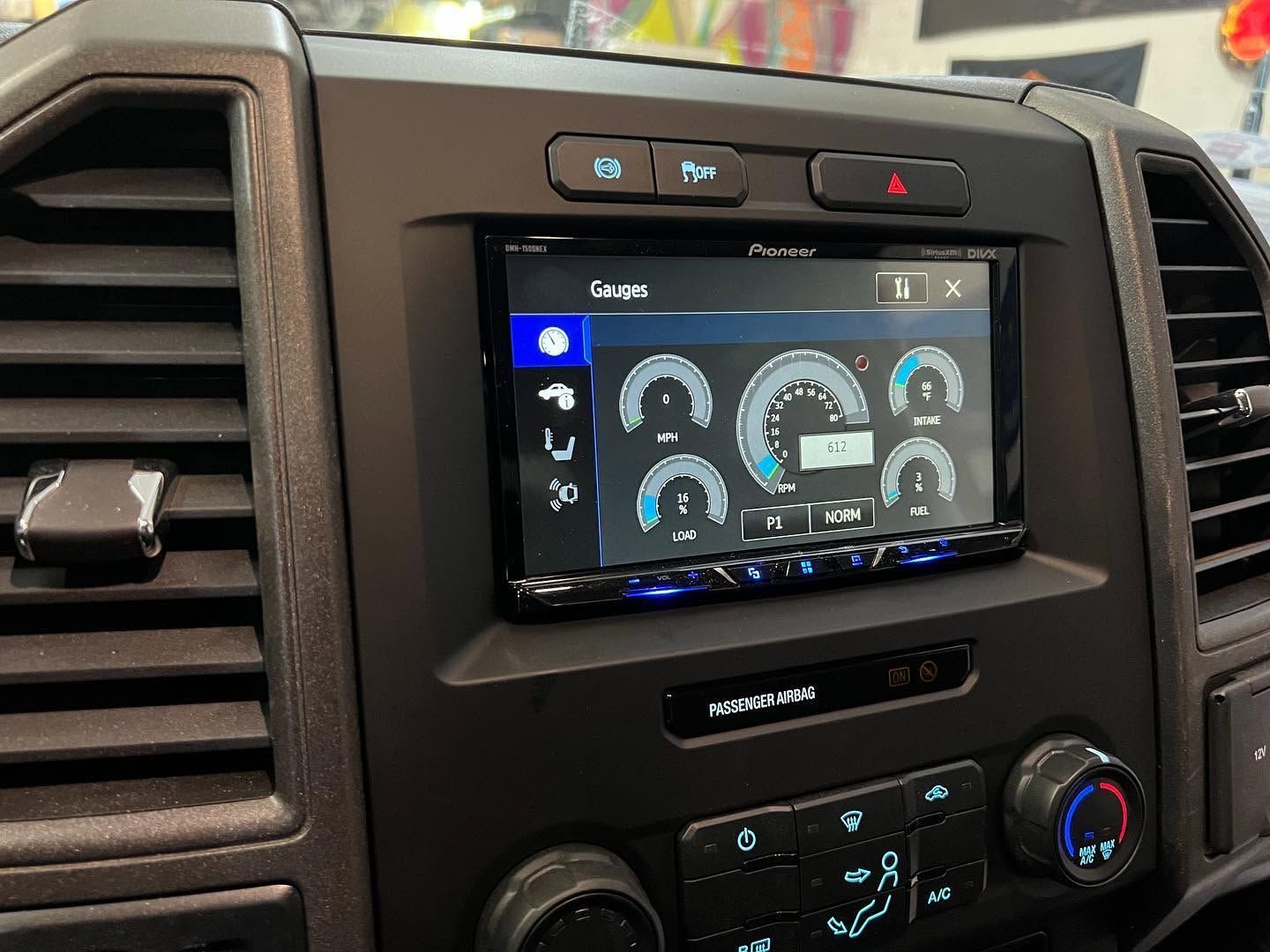 Car dashboard with a touchscreen display showing a gauge-style interface and climate controls beneath it