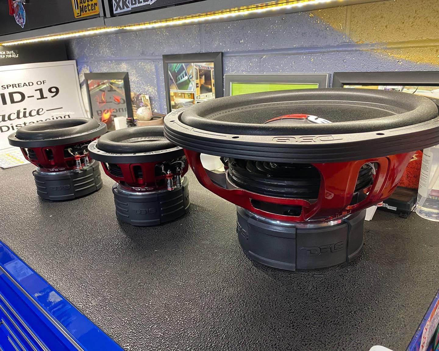 Large red and black subwoofer speakers displayed on a counter in a shop.