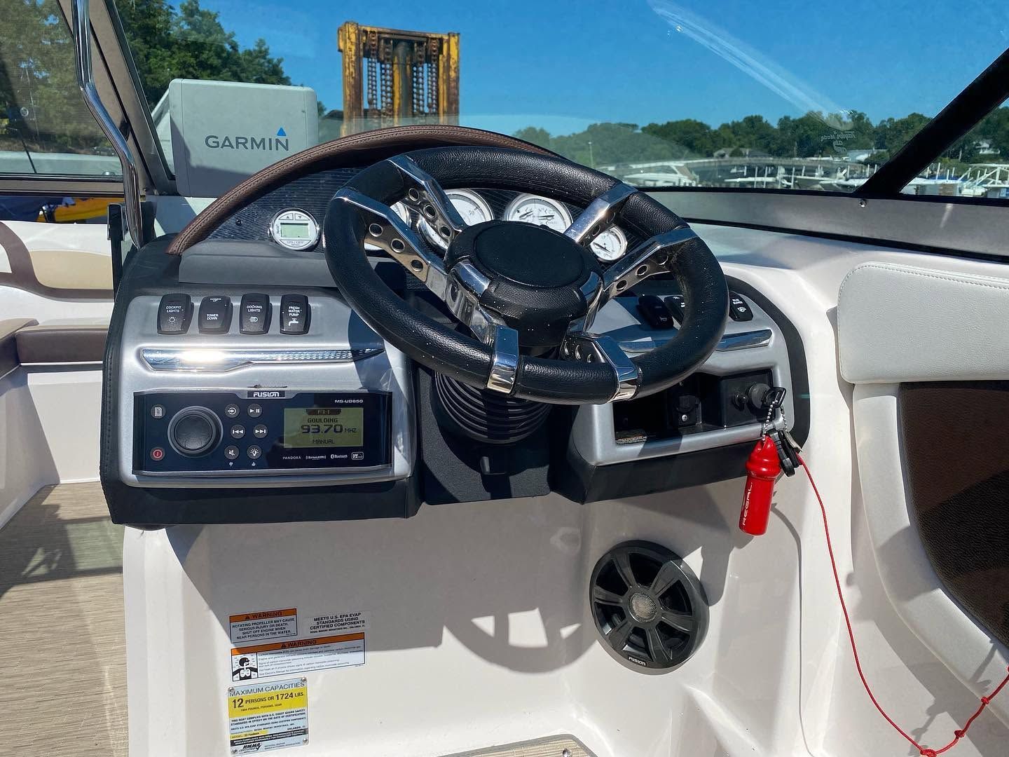 Boat helm with steering wheel, gauges, and red lanyard in a white cockpit