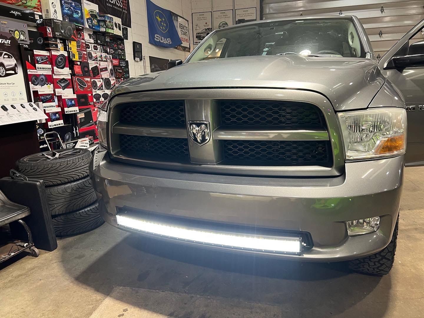 Silver Dodge Ram truck parked indoors with bright LED light bar on the front bumper
