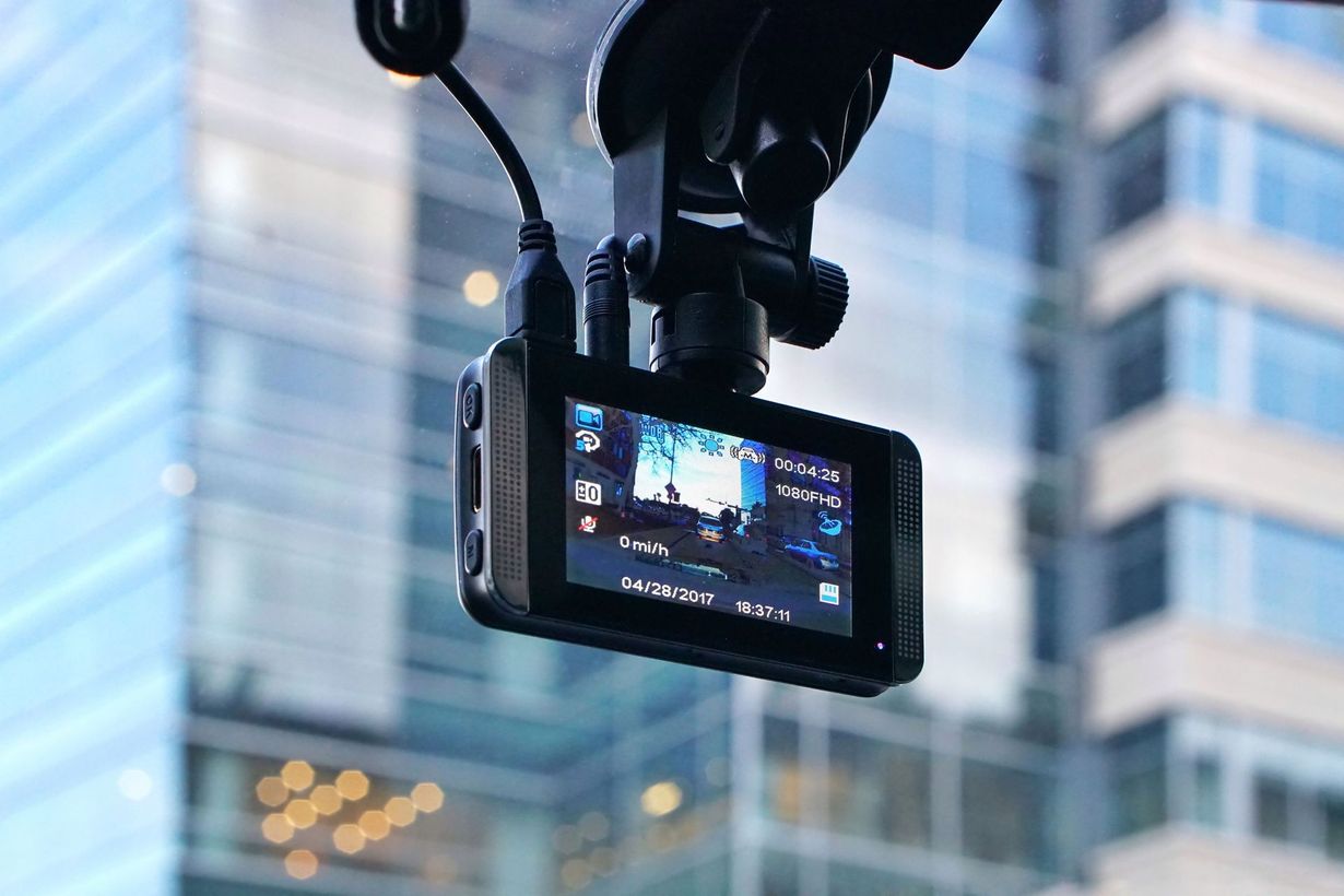 A camera mounted inside a vehicle records a city street through the windshield.