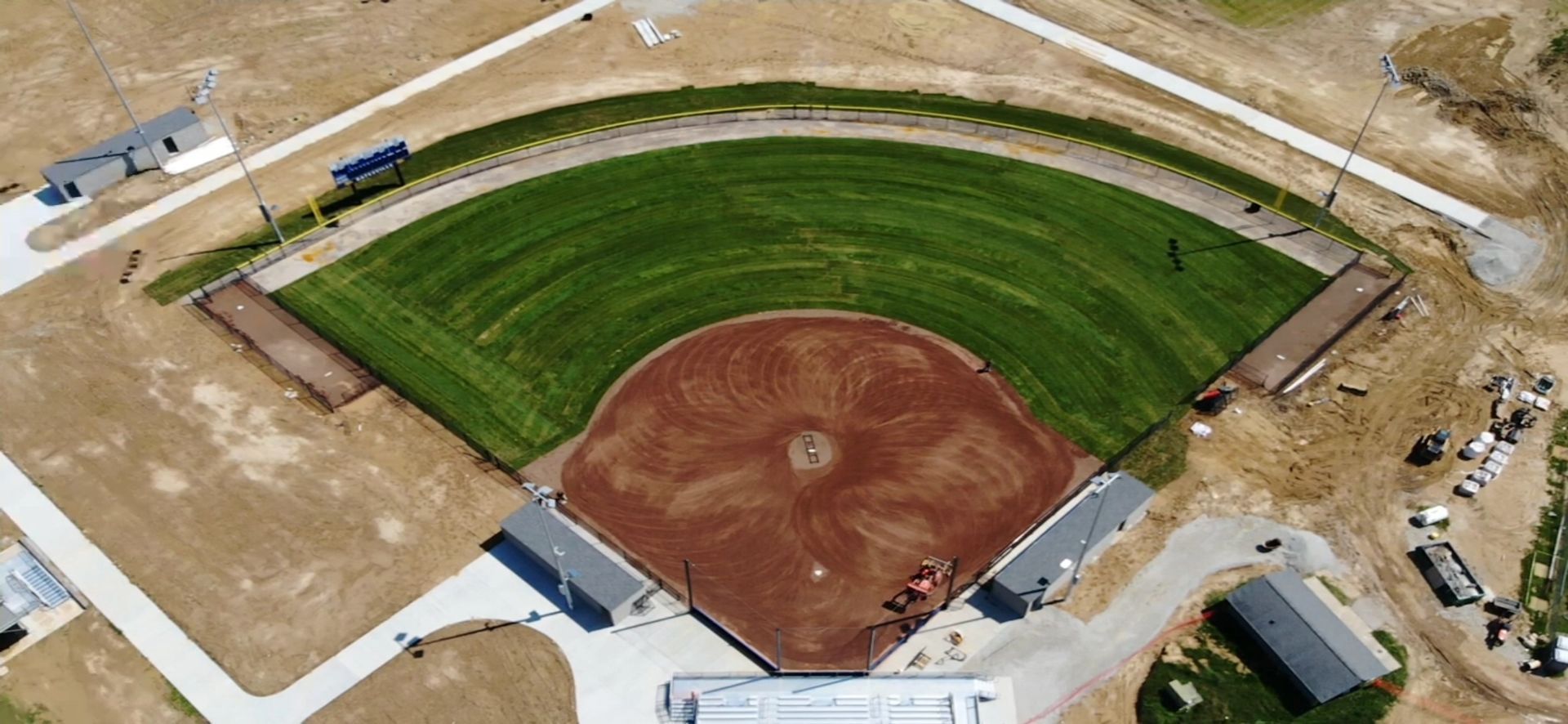 Aerial view of a baseball field with green outfield and brown infield under construction.
