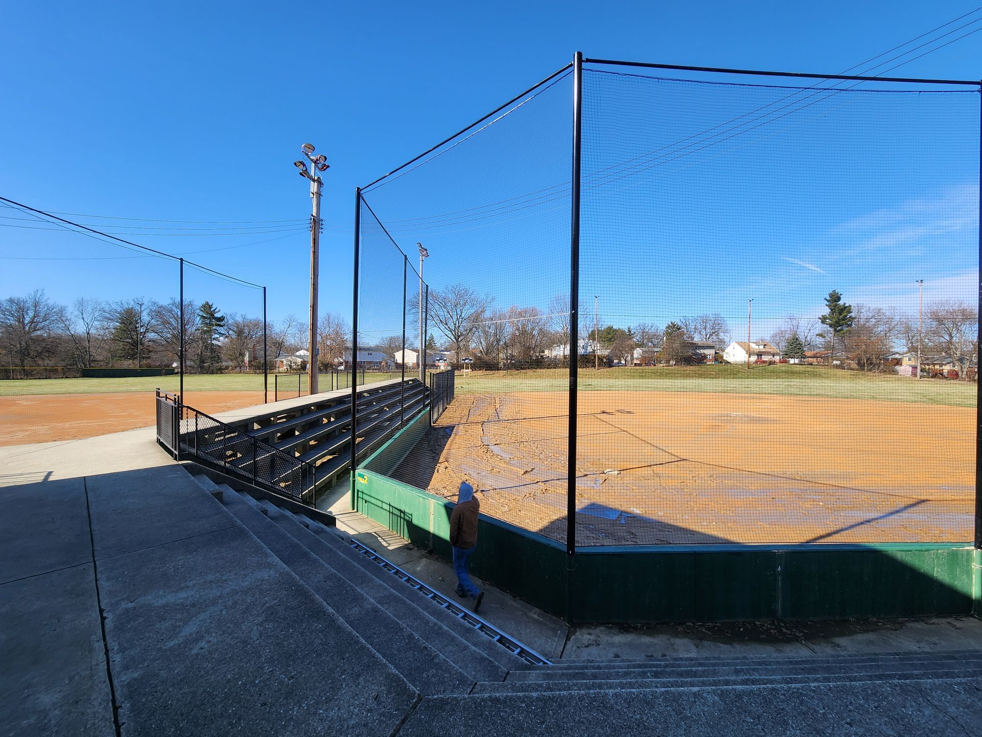 Baseball field with chain-link backstop, bleachers, and blue sky on a sunny day