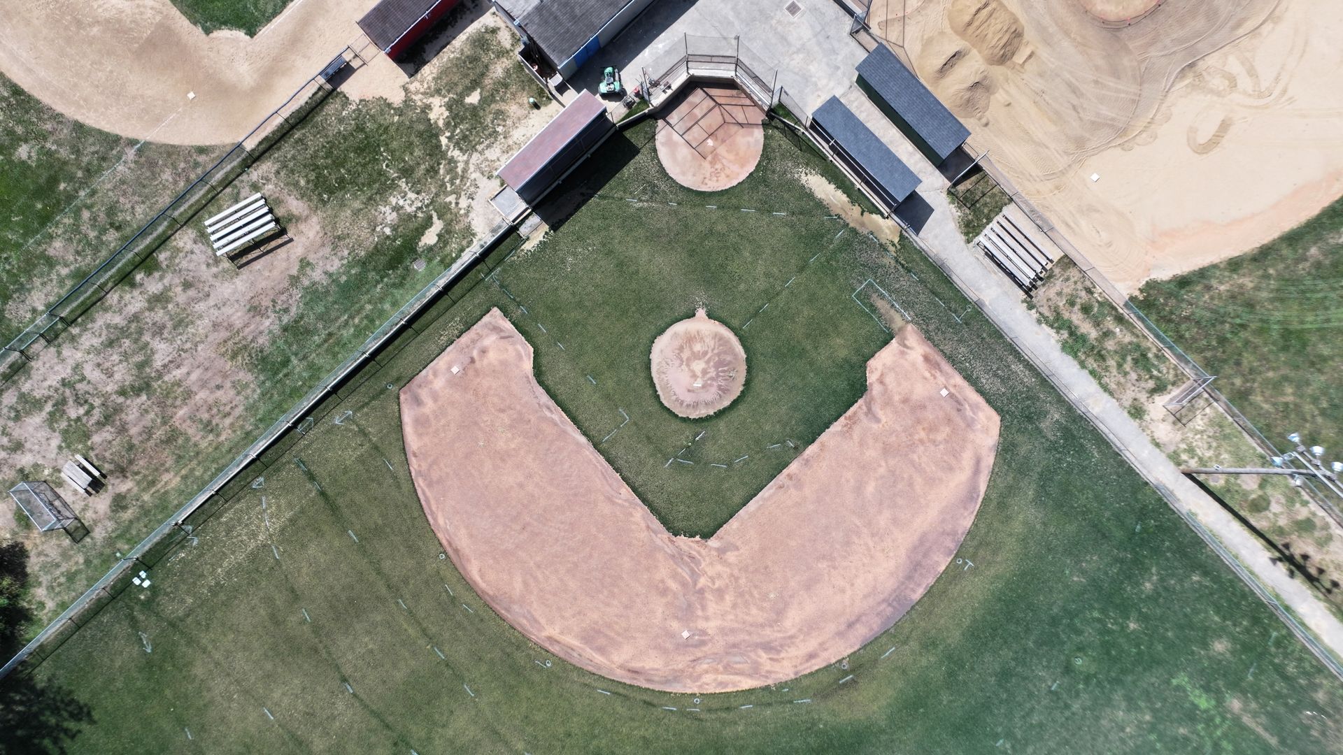 Aerial view of a baseball diamond with a sandy infield and green outfield near a beach.