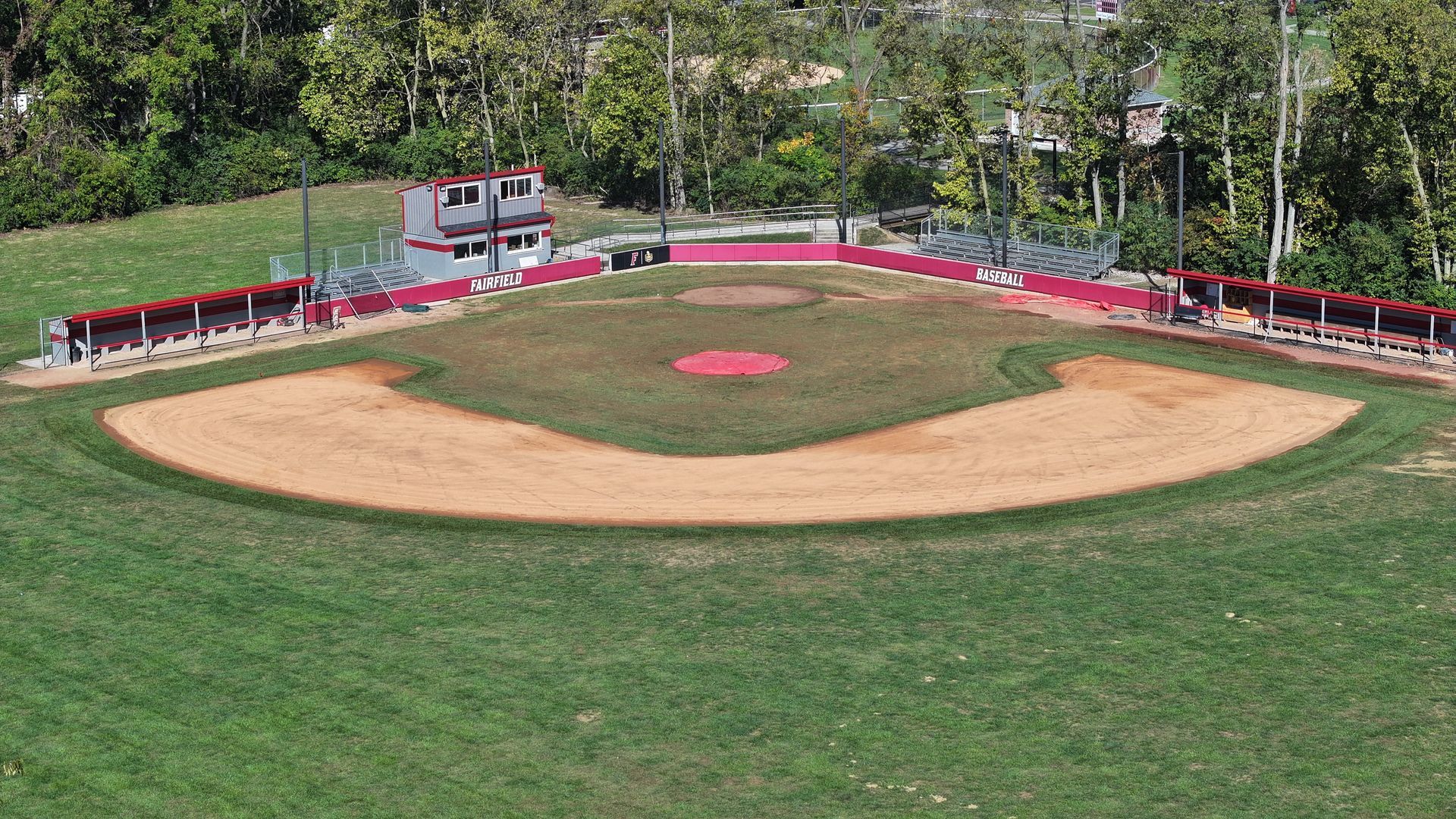 Empty baseball field with red stands and trees in the background