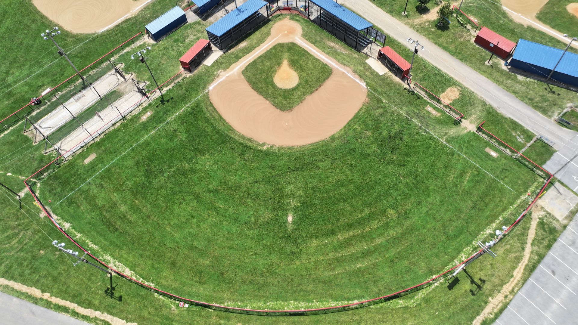 Aerial view of a baseball field with green outfield, brown infield, and surrounding bleachers and buildings