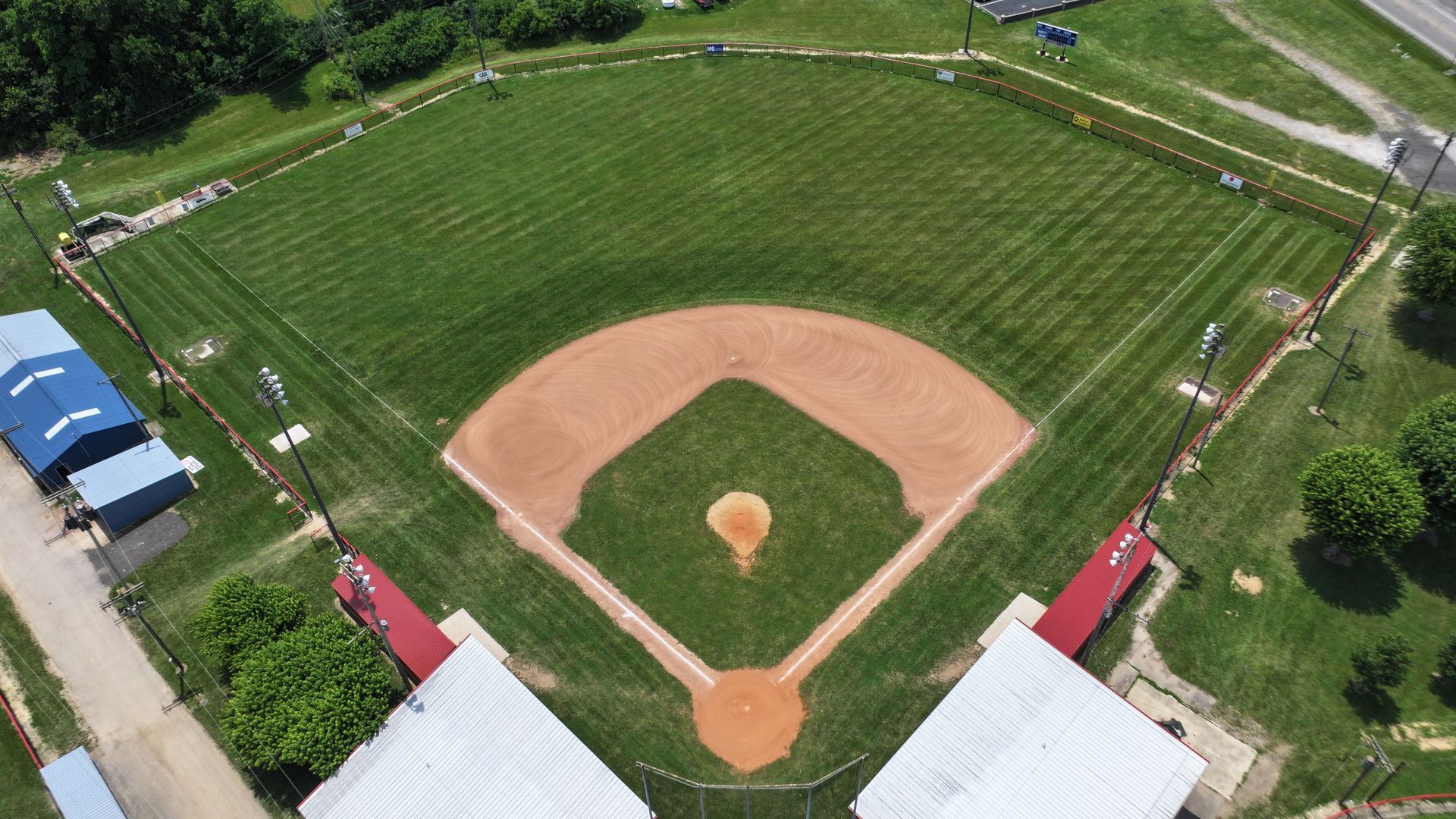 Aerial view of a baseball field with green outfield and brown infield, surrounded by grassy stands