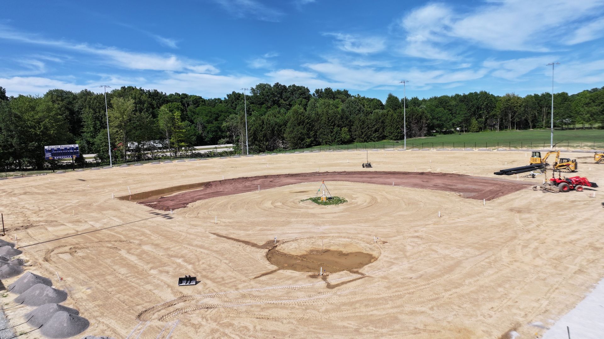 Large sandy construction site with a circular dirt area and equipment under a clear sky