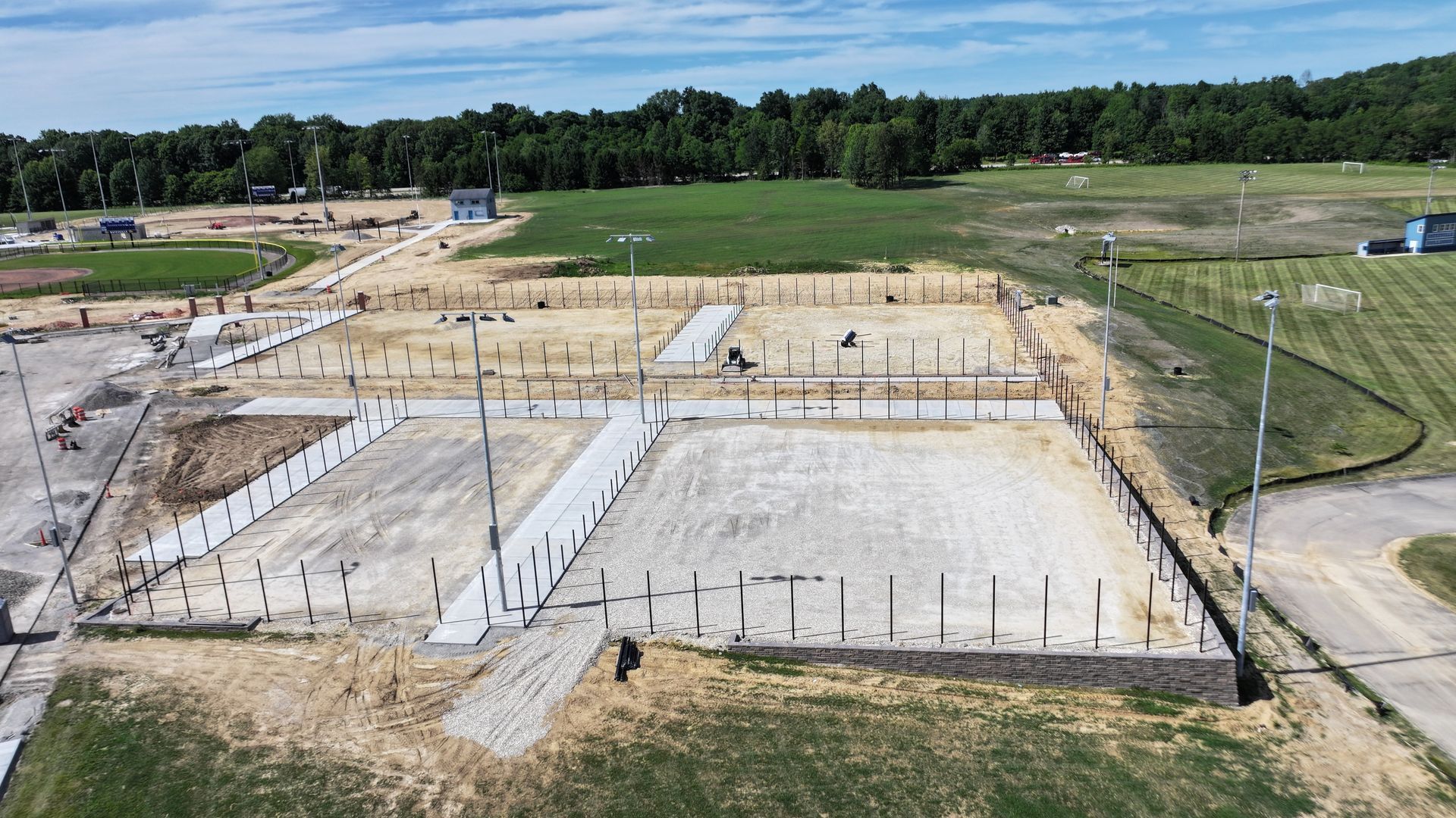 Concrete foundation site under construction with wooden forms, rebar, and surrounding grassy land