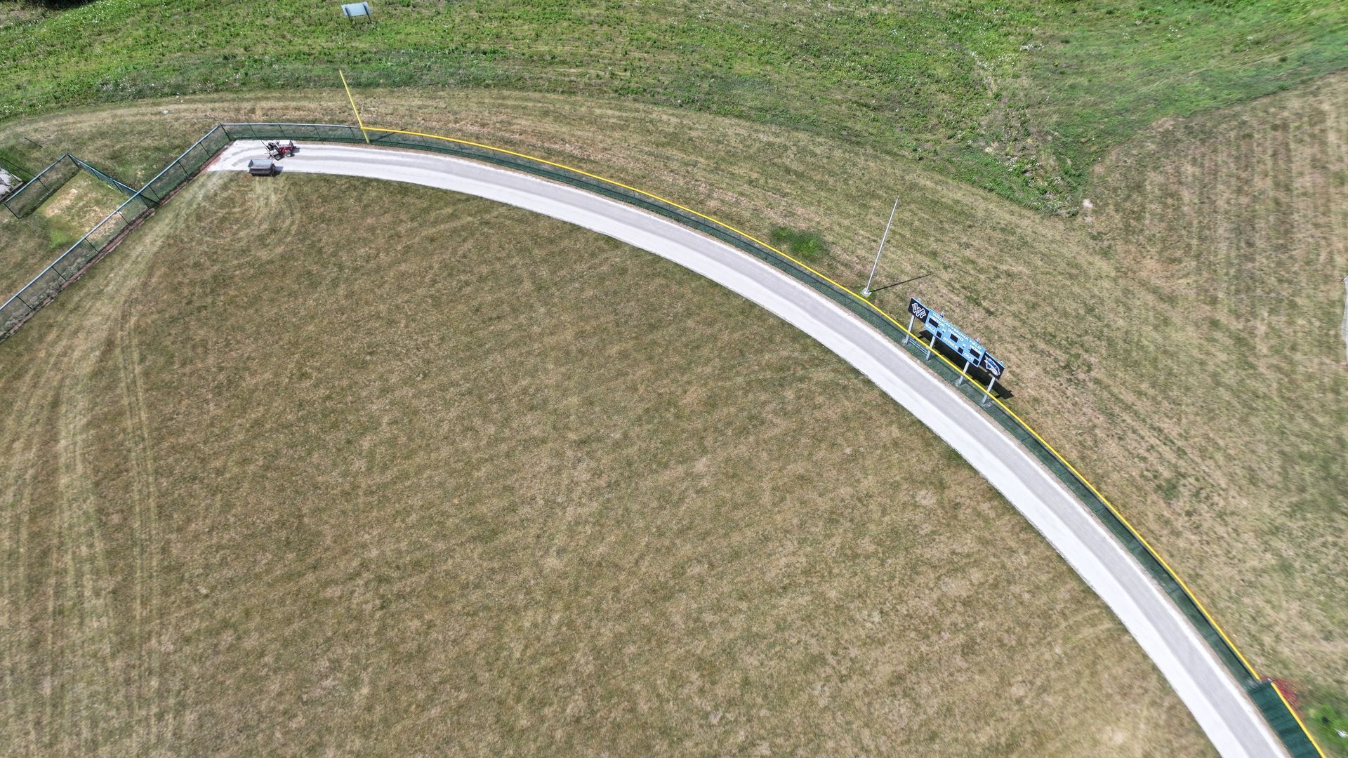 Aerial view of a curving road through grassy fields with a few cars traveling along it
