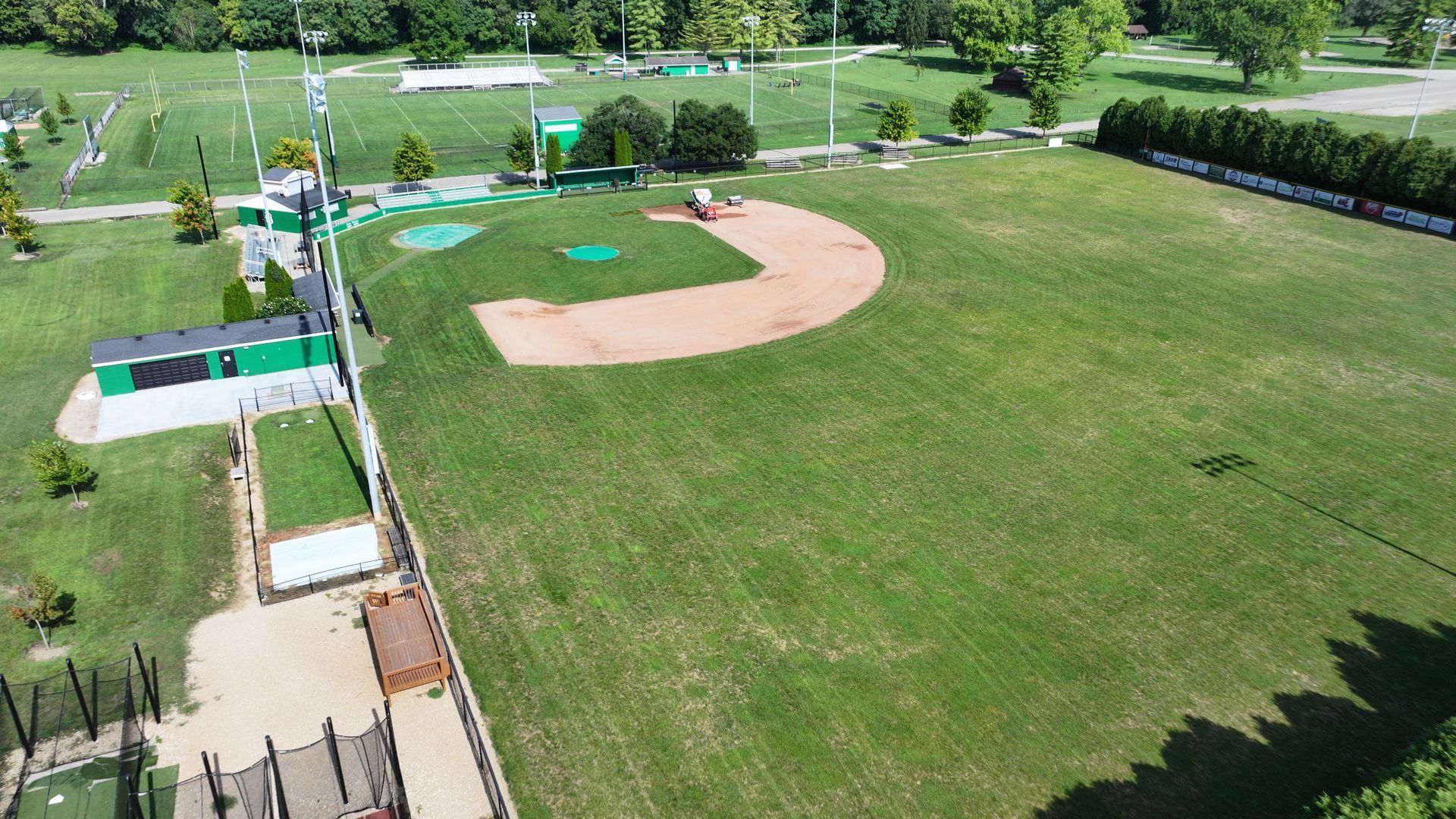 Aerial view of a baseball field beside a large green open park with walking paths and trees