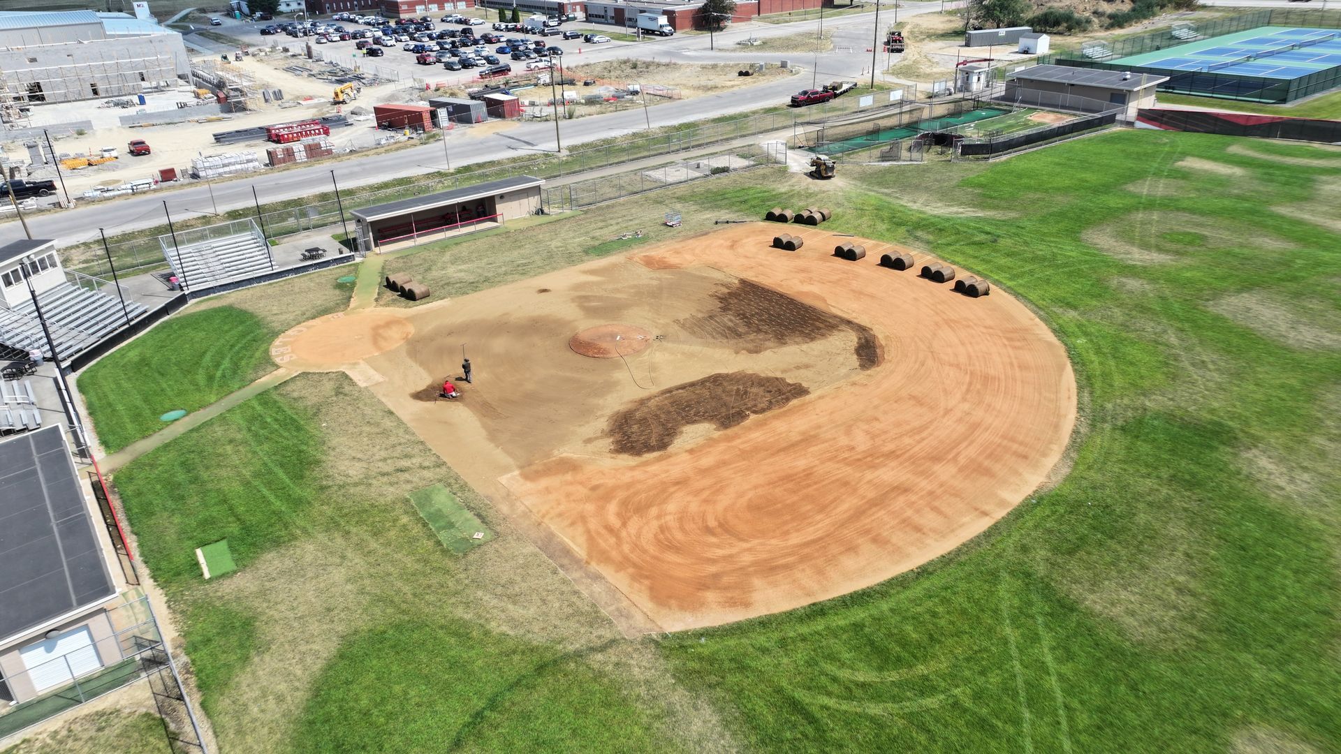 Aerial view of a baseball field under construction with dirt infield and green grass outfield.
