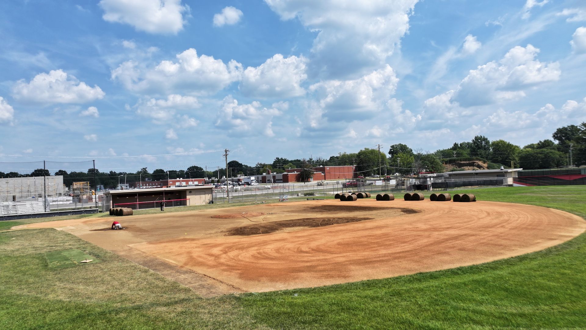 Empty baseball field under a blue sky with scattered clouds, seen from the outfield.