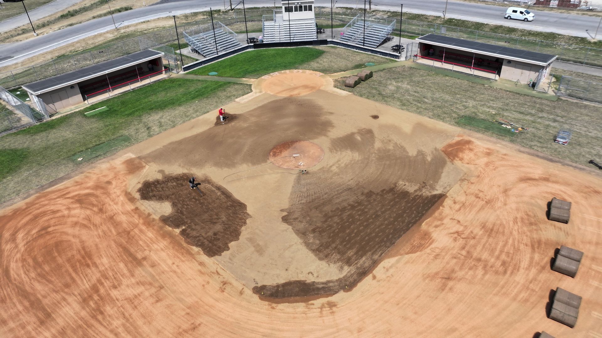 Aerial view of a dirt motocross track under construction with scattered soil piles and a grassy border