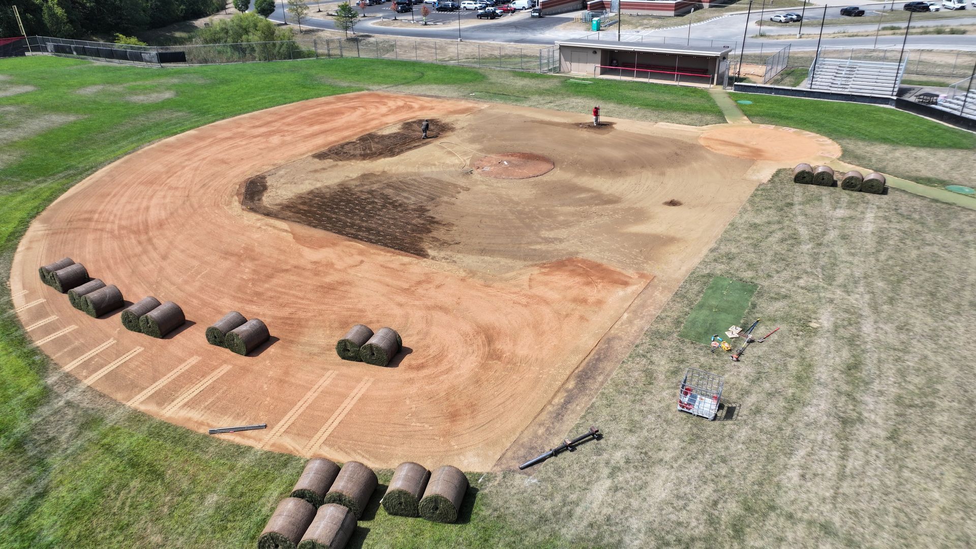 Dirt motocross track with orange-brown jumps, tires marking the edges, and grassy surroundings